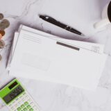 Plicuri etichetate pentru bugete separate și câteva monede pe un birou din lemn, simbol al organizării banilor