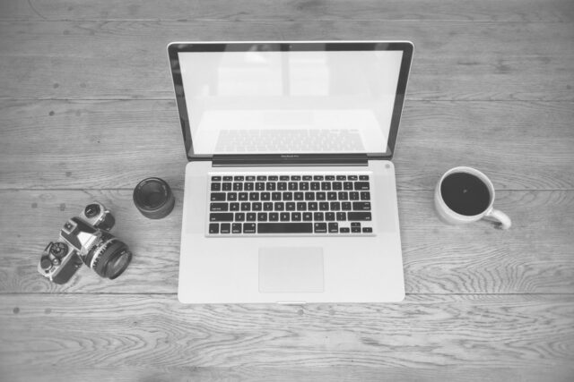 Laptop deschis, un caiet cu schițe de plan de afaceri și o cană de cafea pe un birou de acasă