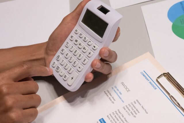 Calculator, facturi și un caiet de evidență pe biroul unui antreprenor care își urmărește încasările